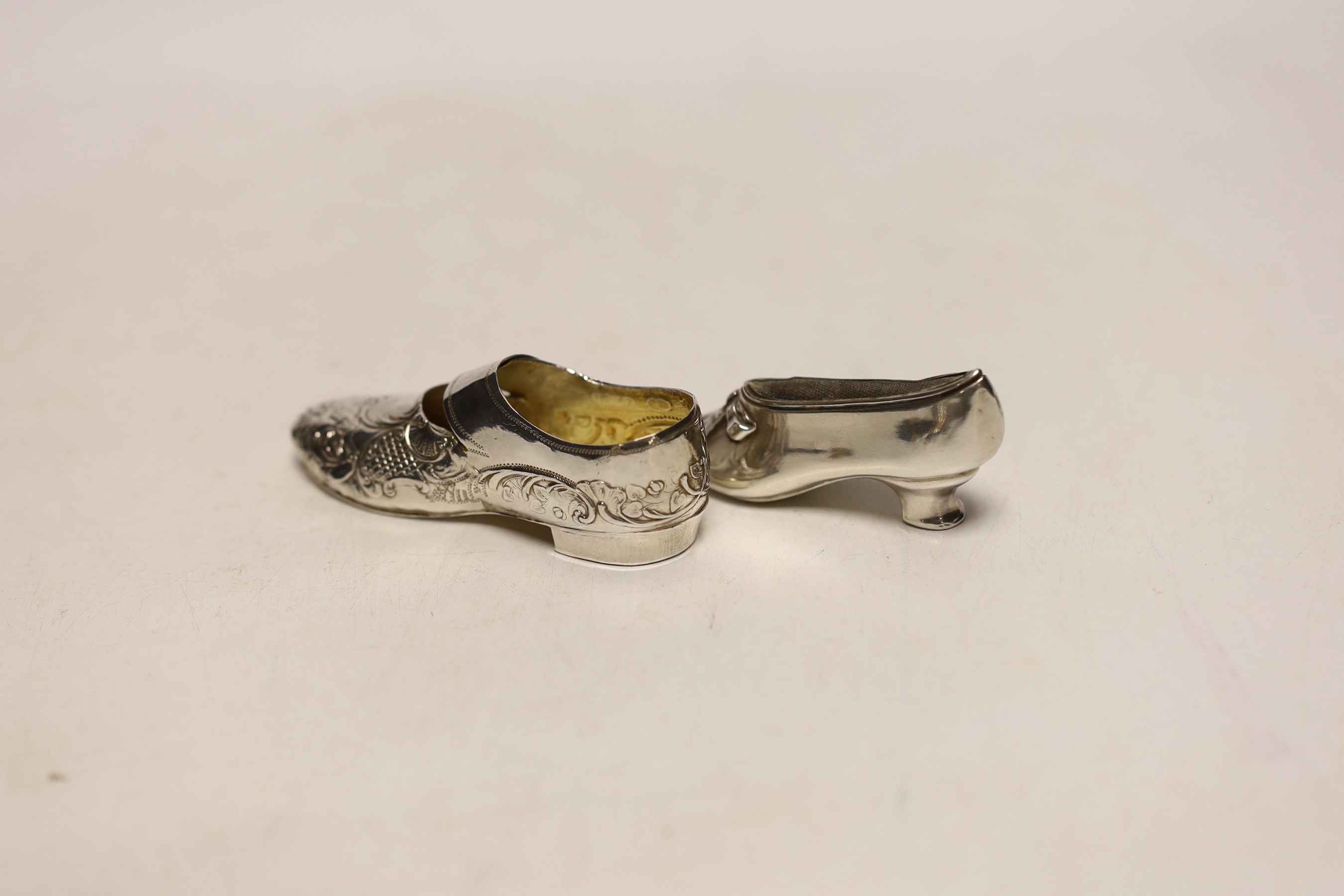 An Edwardian novelty silver pin cushion, modelled as a shoe, Levi & Salaman, Birmingham, 1904, 68mm, together with a silver model of a shoe, import marks for Elly Isacc Miller, London, 1897.
